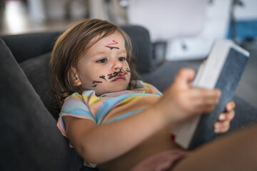 caucasian girl toddler with painted color draws and stains on face