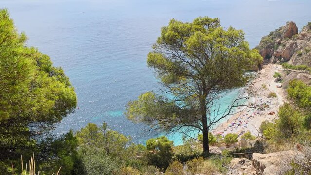 View from the mountain to the beautiful beach in a bay with cliffs, blue skies and azure Mediterranean Sea. Cala del Moraig beach, Benitatxell, Alicante, Spain.