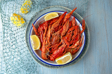 Boiled crayfish or lobster with aromatic herbs and lemon on a blue background. Mediterranean Kitchen. Sea mood menu.