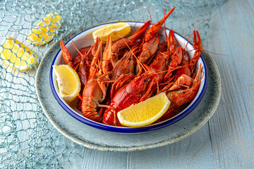 Boiled crayfish or lobster with aromatic herbs and lemon on a blue background. Mediterranean Kitchen. Sea mood menu.