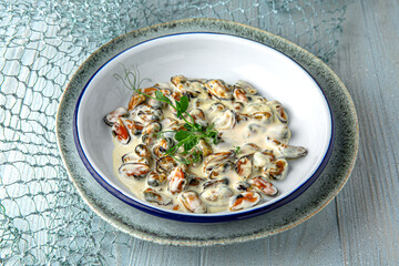 Mussels in creamy sauce on a blue background. Mediterranean Kitchen. Sea mood menu.