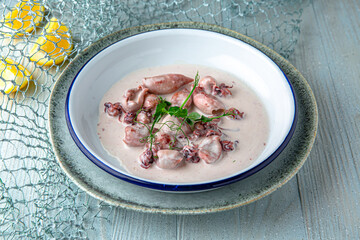 Baby squid in creamy sauce on a blue background. Mediterranean Kitchen. Sea mood menu.