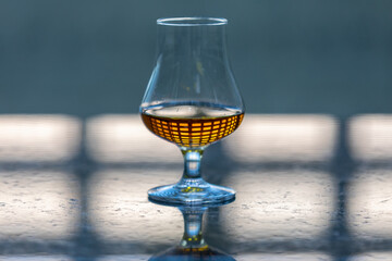Single malt scotch whiskey in glencairn tasting glass with window reflection in liquid