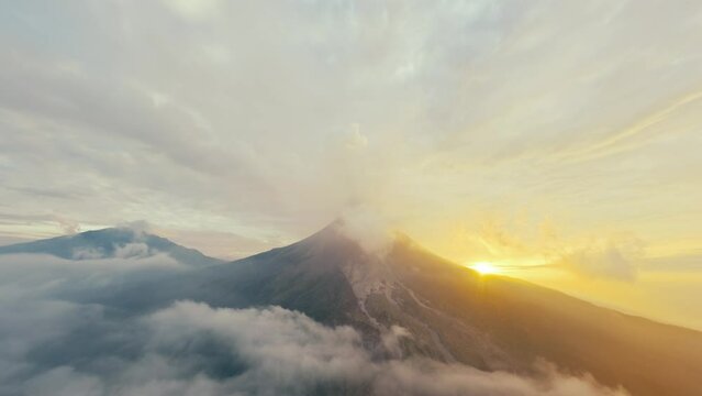 Aerial view peaceful gorgeous active erupting volcano with steam crater clouds at sunset sky. Wild picturesque nature landscape volcanic mountains valley environmental morning disaster concept sunrise