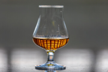 Single malt scotch whiskey in glencairn tasting glass with window reflection in liquid