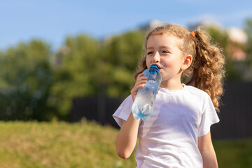 little girl drinking water from bottle in heat. kid suffering from thirst. prevention of dehydration on sunny day. thirsty child drink liquid for hydration, wellness, health. copy space, text