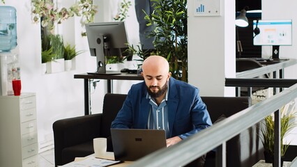 Office manager compares data on laptop to create new report, working with statistics to solve tasks. Unicorn business employee analyzing documents in open space urban building.