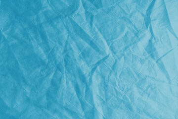 Wrinkled, crumpled blue fabric texture background. Wrinkled and creased abstract backdrop of spunbond textile, wallpaper with copy space, top view.