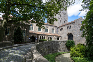 A winding cobblestone pathway leads up a hill to the entrance to the MET Cloisters museum in New York City, USA.