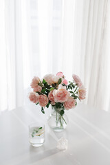 An elegant bouquet of fresh roses and placed by a light-filled window.