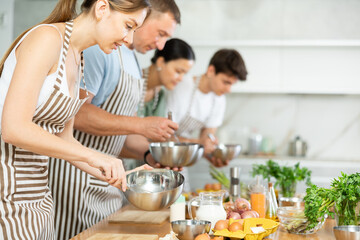 Young woman in apron learning to cook at cooking master class