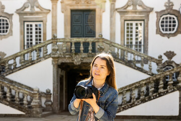 Focused traveler photographer woman with camera taking pictures of medieval architecture of Mateus Palace in Portuguese city of Vila Real on spring day