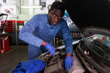 Professional man car mechanician repairing car in auto repair shop