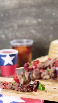 Fiestas Patrias Chile September 18, Independence Day. Empanadas, Anticuchos, mote con huesillo, chicha or wine, Sombrero, huaso, chupallas, emboque, wooden table. Flag and space to copy video vertical