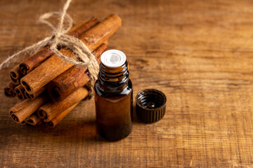 Essential cinnamon oil in a small bottle, ground cinnamon and cinnamon sticks on old wooden background.