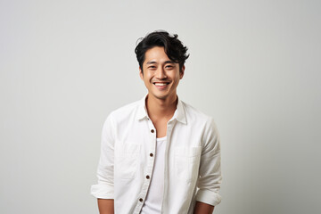 Portrait of a smiling young Asian man standing and looking at the camera with a white background.