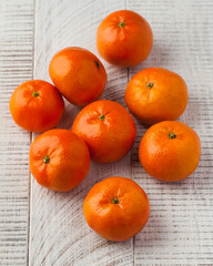A group of ripe tangerines on a light wooden background. 