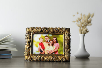 Vintage square frame with family photo, books and vase of dry flowers on wooden table