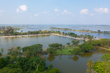 Fototapeta premium Aerial top view of a garden park with green forest trees, river, pond or lake. Nature landscape background, Thailand.