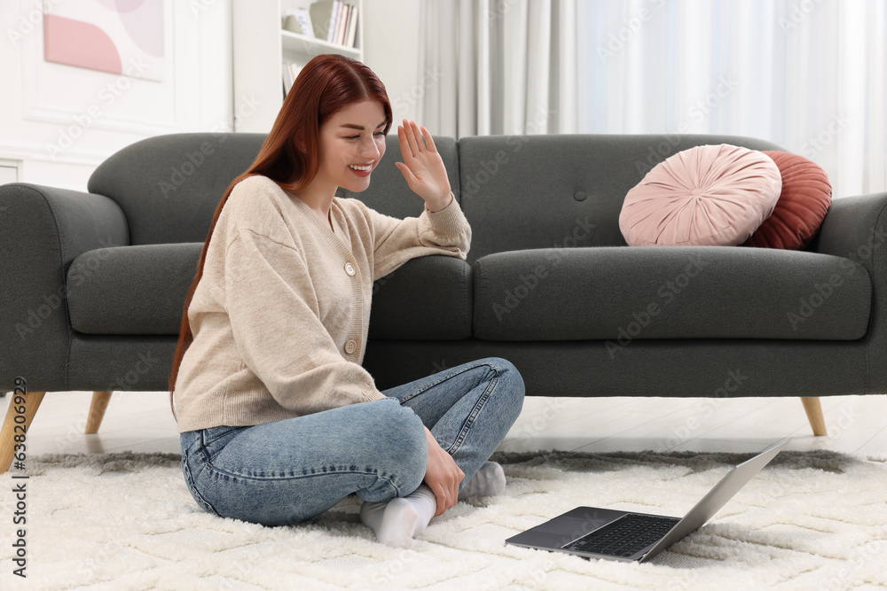 Wall mural Happy woman having video chat via laptop on rug in living room