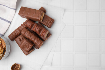 Different tasty chocolate bars on white tiled table, flat lay. Space for text