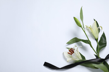Beautiful lilies and black ribbon on white background, top view with space for text. Funeral symbol