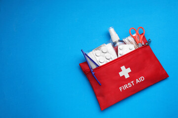 First aid kit on light blue background, top view and space for text
