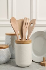 Set of different kitchenware on light gray table near white wall