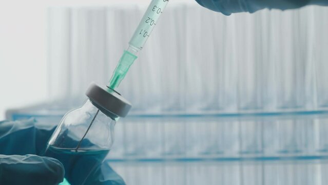 A doctor is drawing up vaccine from phial bottle and filling syringe injection for vaccination. Concept of health care treatment disease prevention and immunization or pandemic vaccine. Close up.
