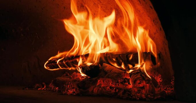 Close-up shot of firewood burning in a stone oven in a restaurant's bakery to bake pizza, pide or bread. Burning fire in stone oven