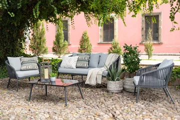Papier Peint photo Jardin Outdoor boutique hotel patio in the garden with a grey sofa set with pillows and chairs on a cobbled floor