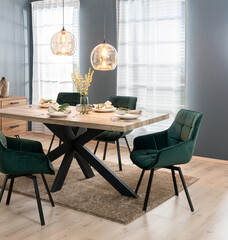 Modern dining room with tableware on a wooden table and a set of green chairs in Scandinavian...