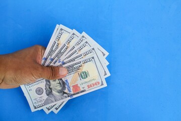 hand holding 100 dollar bill. the concept of receiving salary or income. the concept of counting money or giving money