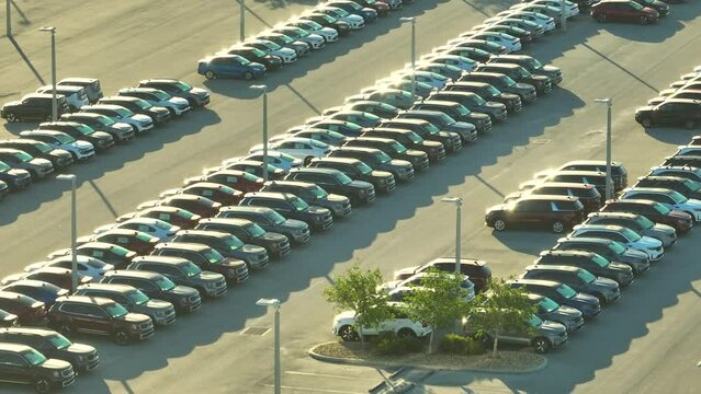 View from above of dealers outdoor parking lot with many brand new cars in stock for sale. Concept of development of american automotive industry
