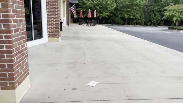Sidewalk in a retail strip mall shopping center American Flag blowing mildly