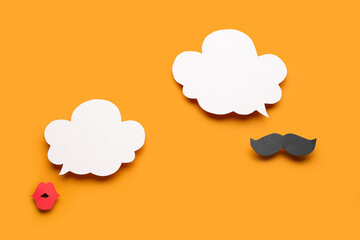 Paper mustache and lips with speech bubbles on orange background