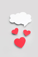 Paper hearts with blank speech bubble on grey background