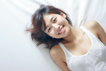 Fototapeta premium Pretty Asian young lady lies on indoor bed. She keeps eyes open and looks satisfied with positive thinking and smiling to camera. Generative AI.