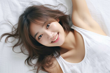 Fototapeta premium Pretty Asian young lady lies on indoor bed. She keeps eyes open and looks satisfied with positive thinking and smiling to camera. Generative AI.