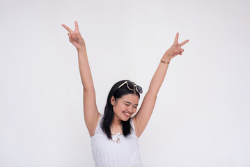 A young asian woman celebrating with arms raised making peace signs. Isolated on a white background.