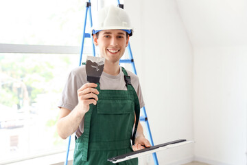 Male worker with putty knives in room