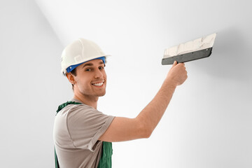 Male worker with putty knife working in room