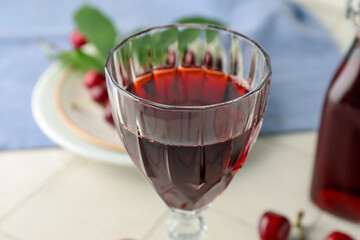 Glass of sweet cherry liqueur with berries in kitchen