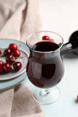 Glass of sweet cherry liqueur with berries in kitchen