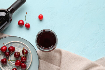 Bottle and glass of sweet cherry liqueur with berries on blue background