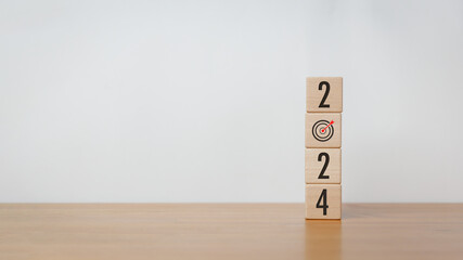 Wood cube block with 2024 text with an arrow icon on wooden table on white background. New year...