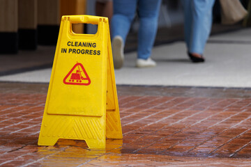 wet floor sign with water drops on wet stone floor. plastic sign warning.