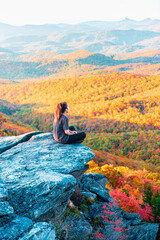 Woman sits on the cliff at Rough Ridge Lookout , Blue Ridge Parkway near Grandfather Mountain in fall season.