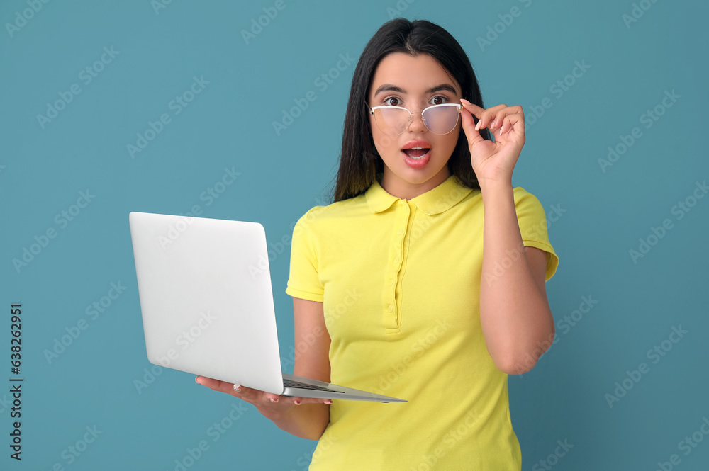 Poster shocked young female programmer with laptop on blue background