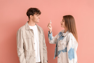 Young couple with key from house on color background